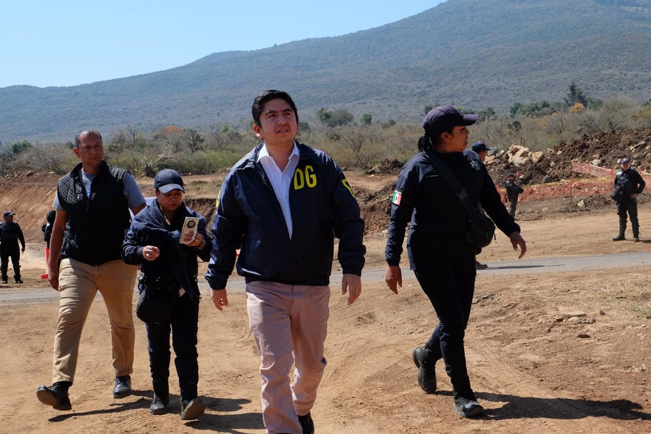 Salvador J. Vazquez Villa recorre a pie una zona de obra carretera junto a personal de seguridad, con un cerro al fondo.